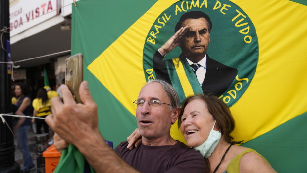Apoiadores do presidente brasileiro Jair Bolsonaro posam para fotos em frente ao seu retrato durante sua campanha de reeleição na semana passada.