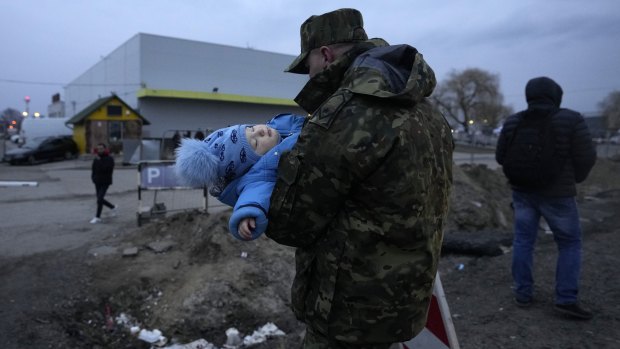 A Polish soldier carries a baby of a Ukrainian refugee upon their arrival at the border crossing in Medyka, south-eastern Poland