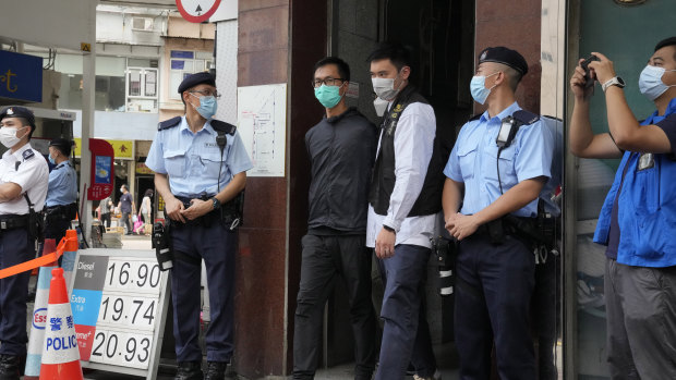 Simon Leung Kam-wai, fourth from right, a committee member of the Hong Kong Alliance in Support of Patriotic Democratic Movements of China, is escorted by police during an investigation of the June 4th Museum in Hong Kong. 