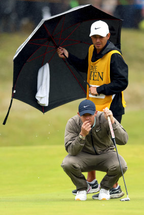 Rory McIlroy prepares to putt in the rain.