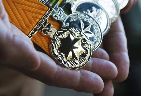 Gavin Stevens holds his medals including the Medal for Gallantry (orange ribbon).