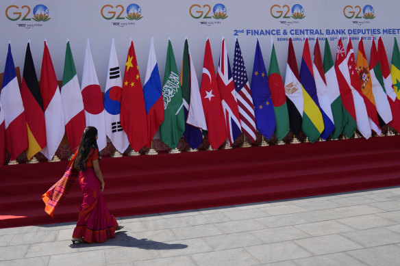 A delegate walks past a display of flags of participating countries at the venue of G20 financial conclave on the outskirts of Bengaluru, India on Wednesday.