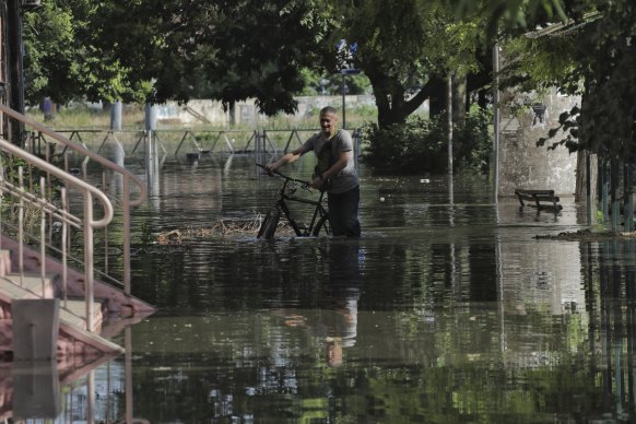 A man pushes his bicycle along a flooded street in Kherson.