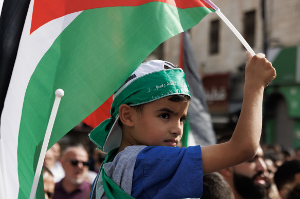 ХАМАС не является маргинальным движением, но пользуется народной поддержкой среди палестинцев.  Мальчик в повязке ХАМАС держит палестинский флаг во время сбора протестующих в Рамалле на Западном Берегу. 