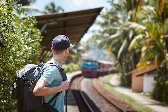 A solo backpacker waits for a train on the platform of a Sri Lankan railway station.