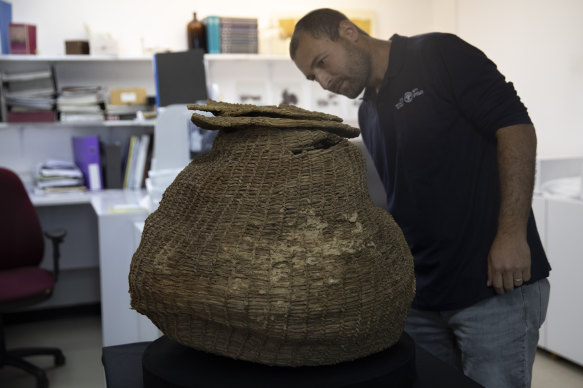 Archeologist Haim Cohen examines a woven basket that was found during a sweep of more than 500 caves.