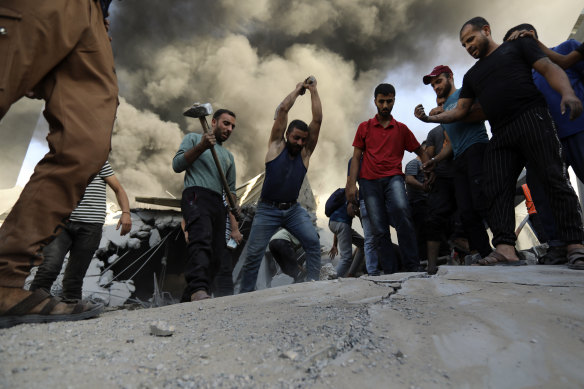 Palestinians strike the concrete while looking for survivors under the rubble of a destroyed house following an Israeli airstrike in Gaza City.