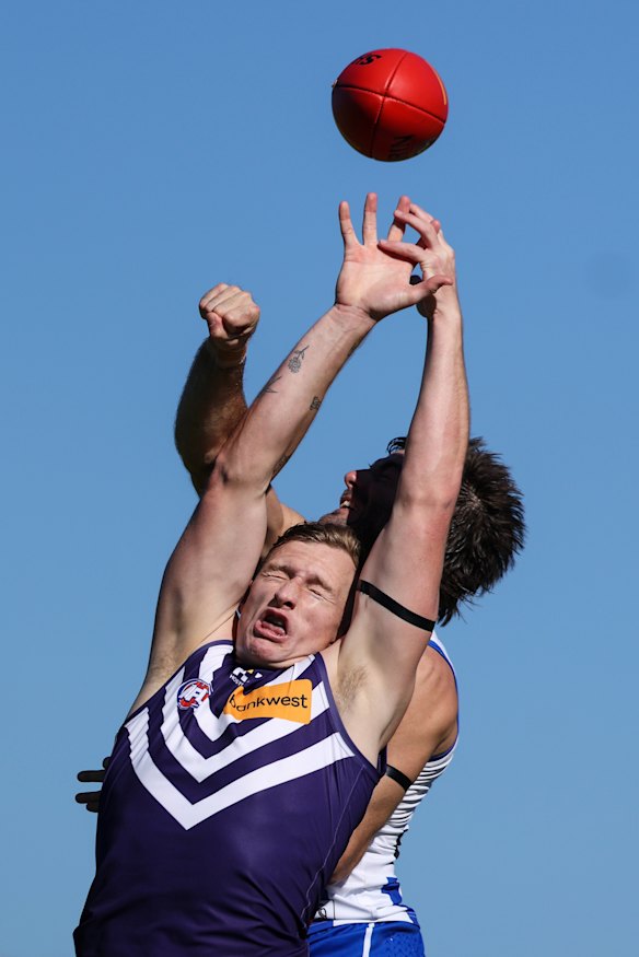 Josh Treacy of the Dockers and Luke McDonald leap for the ball.