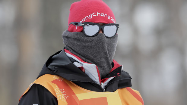 A race worker covers up from the cold during the men's 15km skiathlon cross-country event.