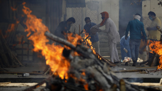 Multiple funeral pyres of COVID-19 victims burn as relatives perform last rites at a crematorium in Delhi, India.