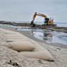 The sandbags being installed in front of Inverloch Surf Life-Saving Club in 2022, after erosion swallowed much of the beach protecting it since 2010.