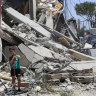 A Lebanese family stands next to a destroyed building that were hit by an Israeli airstrike, in Aita al-Shaab, a border village.