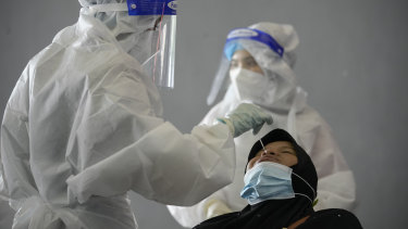 A medical worker collects swab sample from a woman during coronavirus testing at a COVID-19 testing center in Shah Alam, outskirts of Kuala Lumpur, Malaysia,