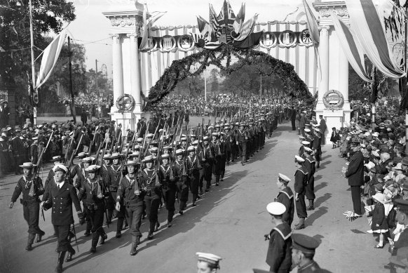 Troops marching through a decorated archway on Macquarie Street during peace celebrations.