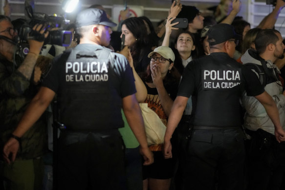 Police restrain fans gathering outside the hotel.