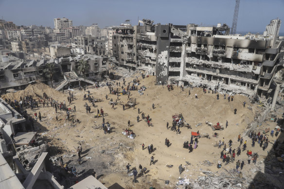 Palestinians walk through the destruction left by the Israeli air and ground offensive near Al Shifa Hospital in Gaza.