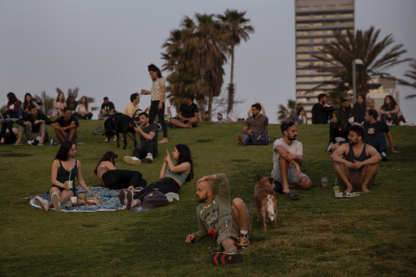 People without face masks watch the sunset, in Tel Aviv, after Israel lifted its public mask mandate.