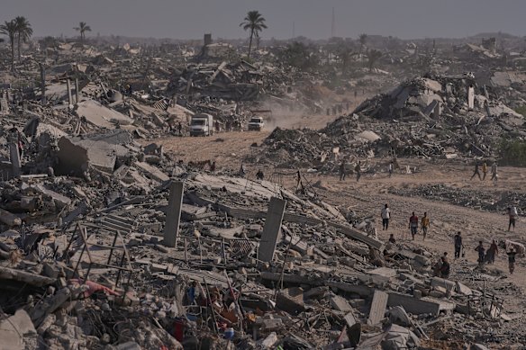 Palestinos deslocados caminham pelas ruínas de Khan Younis, que tinha uma população pré-guerra de mais de 200 mil habitantes.