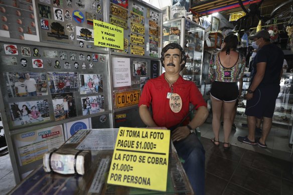 Tourists buy souvenirs of the late drug lord Pablo Escobar, featured as a statue with a sign that says one will be charged for taking photos inside a store in Doradal, Colombia.