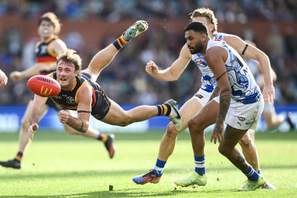 Adelaide’s Luke Pedlar fires off a handball with Tarryn Thomas in pursuit.