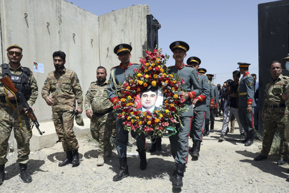 Afghan honor guards hold a wreath of flowers containing a portrait of Dawa Khan Menapal, director of Afghanistan’s Government Information Media Centre who was shot and killed in Kabul, Afghanistan,  on August 7.
