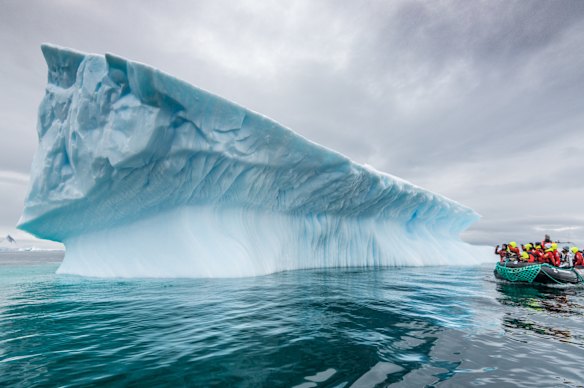 A Zodiac pauses at an iceberg.