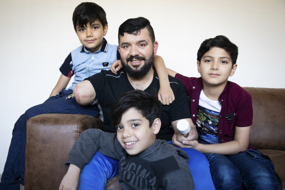 Eight-year-old twins Ahmed and Mohammed al-Shnen and 10-year-old Ali (right) with their father at his home. 