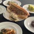 The humble hot dog is reinvented at the Paris OlympicVillage as a meat-free “not-dog” with onions and pickled cabbage, slathered in honey-mustard sauce. 