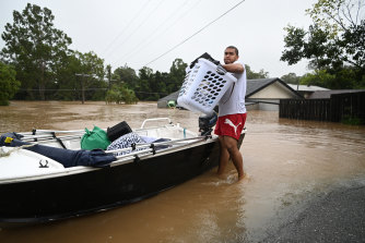 A man carries his belongings as people evacuate homes inundated by floodwater at Goodna in Brisbane’s west. 