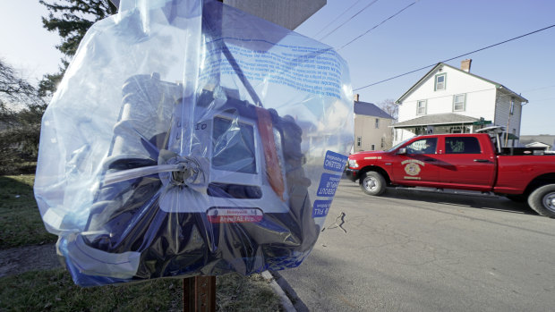 An air quality monitoring device hangs from a stop sign in eastern Palestine, Ohio, as clean-up efforts continue following the derailment of a Norfolk Southern freight train over a week ago.