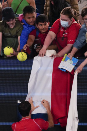 Daniil Medvedev of Russia autographs a flag after defeating American Marcos Giron in the first round.