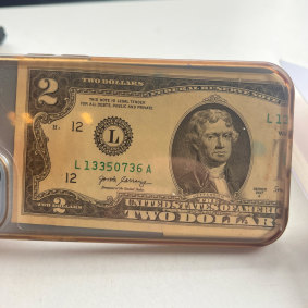 Trbojevic’s two-dollar bill in the clear case of his mobile phone.