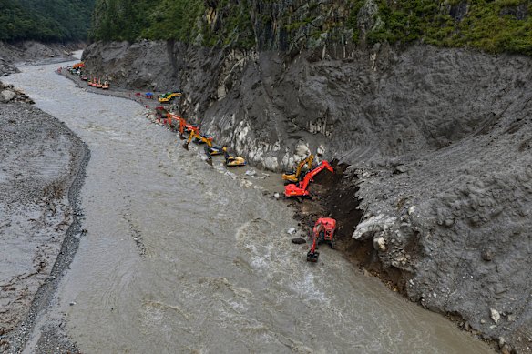 Chinese excavators work to remove mud and debris from the road next to a still-swollen river in Gyirong County in the Tibetan Autonomous Region. 