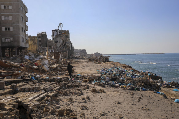 A Palestinian man walks on the beach by destroyed buildings in Gaza City during the November ceasefire.