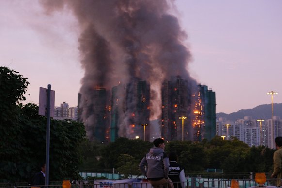 People look on as thick smoke and flames rise from a major fire at Wang Fuk Court in Hong Kong’s Tai Po district.