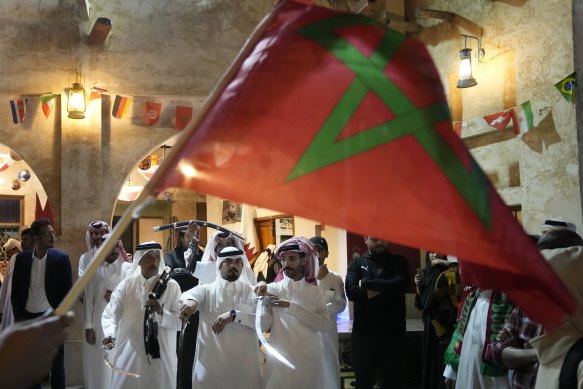 A man waves a Moroccan flag as people celebrate in the Souq in Doha after Morocco’s win over Portugal.