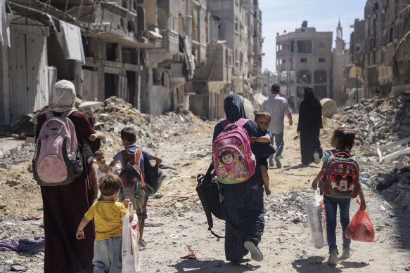 Palestinian women and their children walk through destruction in the wake of an Israeli air and ground offensive in Jebaliya, northern Gaza, at the weekend.