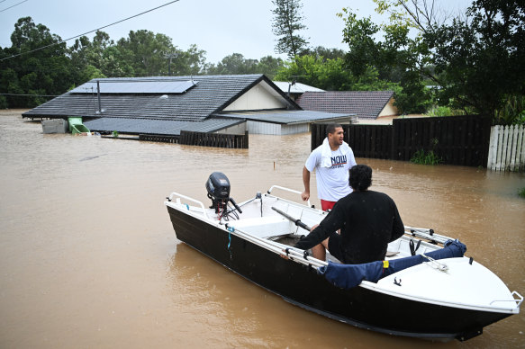 Residents take to the water in a boat as people evacuate homes inundated by flooding in Ipswich’s Goodna.
