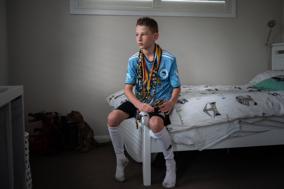 Kingston Smith wearing his soccer medals and “beads of courage” necklace, with beads representing every procedure during his cancer treatment.