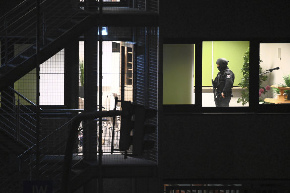 Police officers in special equipment walk through a Jehovah’s Witness building in Hamburg, Germany,