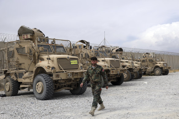An Afghan army soldier walks past Mine Resistant Ambush Protected vehicles, MRAP, that were left after the American military left Bagram air base, in Parwan province north of Kabul, Afghanistan, on July 5. 