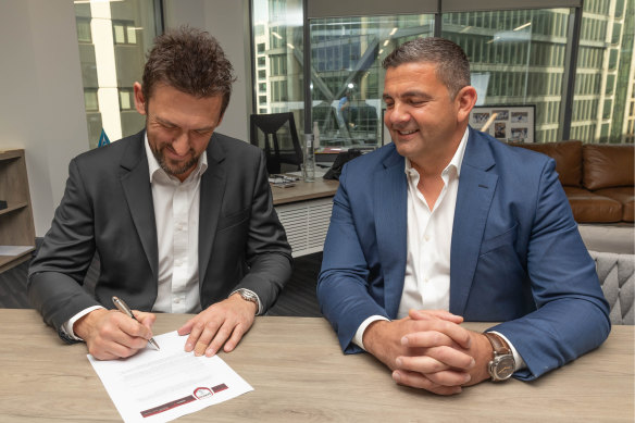 Xanthi FC owner Bill Papas watches on as Tony Popovic puts pen to paper with the Greek club.