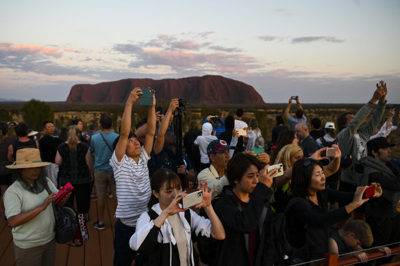 Tourists taking photographs of the rising sun near Uluru on October 12. 