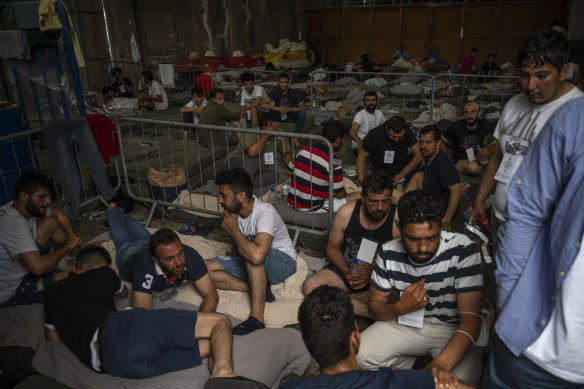 Survivors of a shipwreck sit inside a warehouse where are taking shelter at the port in Kalamata.