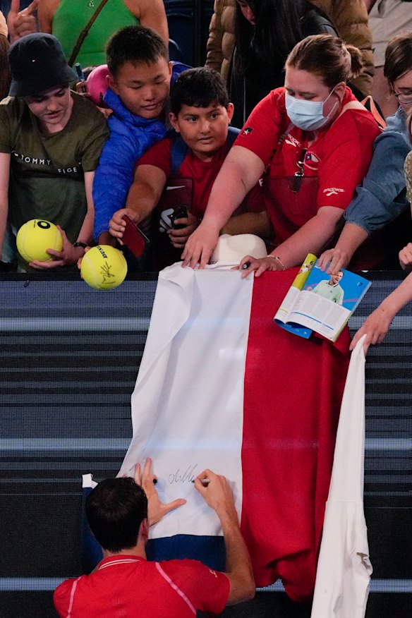 Daniil Medvedev of Russia autographs a flag after defeating American Marcos Giron in the first round.