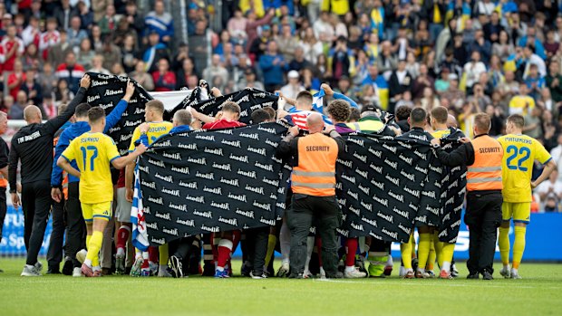 Denmark and Ukraine players accompany Eriksen to a waiting ambulance.