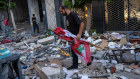 A man picks up a Lebanese flag from the rubble after an Israeli airstrike on an apartment block in Beirut on Thursday.