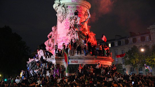 Demonstrators climb on the Monument a la Republique during a protest following the legislative election results.