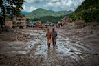 Residents walk along a muddy road following the flash floods in Trishuli, Nepal.