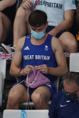 Tom Daley of Great Britain knits as he watches the Women’s 3m Springboard Final.